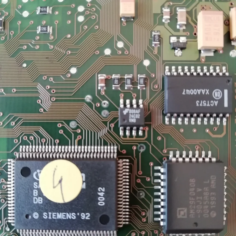 Close-up of an ECU circuit board: the small 8-pin EEPROM chip (marked 24C02) stores important data like immobilizer codes and can be read or reprogrammed.